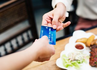 woman handing over card to pay in restaurant