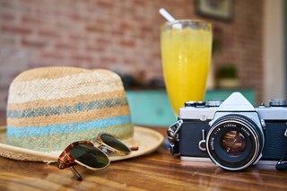 camera hat and sunglasses on wooden table