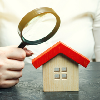 a person looking at a model house with a magnifying glass
