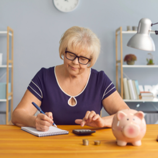 elderly woman doing paperwork with piggy bank