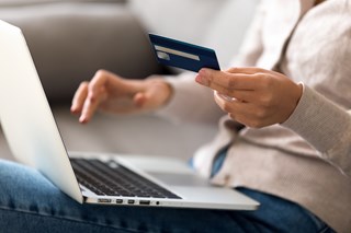 a person holding a credit card using a laptop