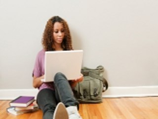 student sitting on floor looking at laptop