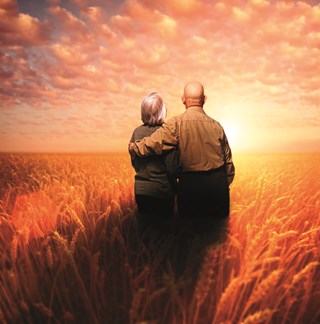 elderly couple looking across cornfield at sunset