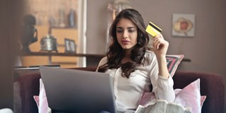 woman looking at laptop holding bank card
