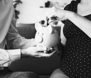 black and white image of woman putting coins into a piggy bank