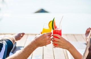man and woman holding up drinks while relaxing outside in summer