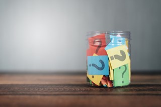 paper with question marks in clear jar