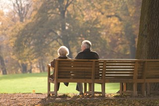elderly couple sat on a bench in the park