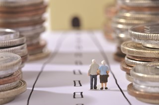 figurine of old people amongst coin stacks