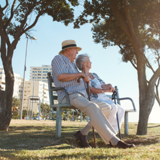 Older couple sitting together on a bench looking into the distance