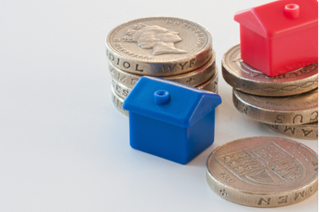 plastic monopoly houses sitting on top of pound coins