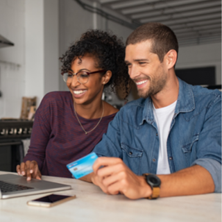 happy couple using a laptop with bank card in their hands