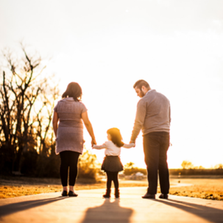 a family of three walking into the sunset