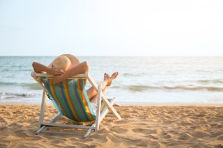 person laying on a sun-lounger on the beach