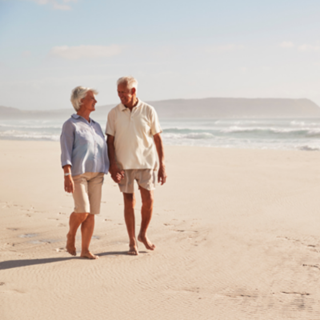 elderly couple wandering down the beach
