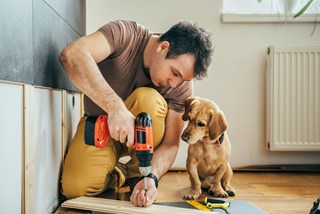 a man doing some DIY with a dog next to him